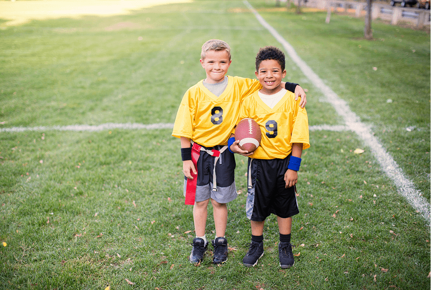 Boys holding football on grassy field